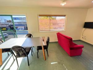 罗托鲁瓦Stay Hostel Rotorua的一间带桌子和红色椅子的用餐室