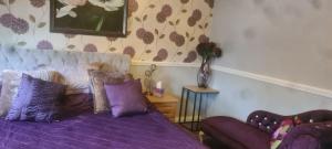 布里真德Parc Lodge Guesthouse的一间卧室配有一张紫色的床和一张沙发
