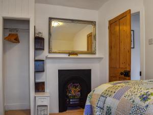 水上伯顿Chapel House的一间卧室设有壁炉,上面有镜子