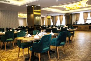 巴士拉Move npic Zenat al Hayat Hotel的餐厅设有木桌和绿色椅子