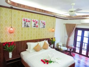 琅勃拉邦湄公河魅力河畔酒店的卧室配有带鲜花的白色床
