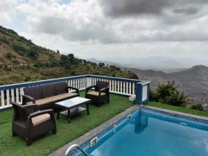 瓦伊Hilltop Resort and Agro Tourism Wai, Near Panchgani的阳台设有游泳池、椅子和桌子。