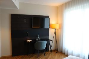 安德纳赫EINSTEIN Hotel am Römerpark的一间房间,配有一张桌子和一台墙上的电视