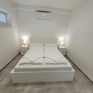 福纽德Szabadszél Apartmanok的白色的房间里一张白色的床,配有两盏灯