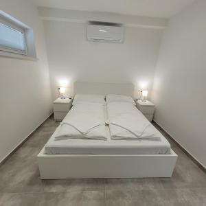福纽德Szabadszél Apartmanok的白色的房间里一张白色的床,配有两盏灯