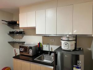 巴科洛德One Regis Bacolod- Upper East Studio Room的厨房配有白色橱柜、水槽和电器