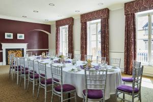 杜伦Delta Hotels by Marriott Durham Royal County的带窗户的客房内一张带紫色椅子的长桌