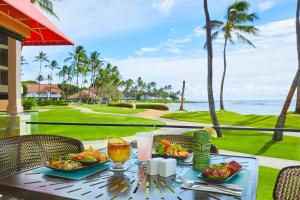 科洛阿Sheraton Kauai Resort Villas的一张桌子,上面放着食物和饮料,还有大海