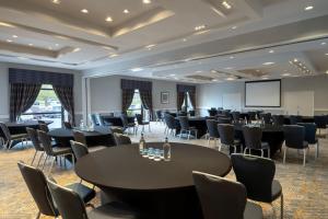 北安普敦Delta Hotels by Marriott Northampton的一间会议室,配有桌椅和屏幕