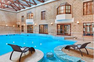 梅德斯通Delta Hotels by Marriott Tudor Park Country Club的大楼内一个带两把椅子的大型游泳池