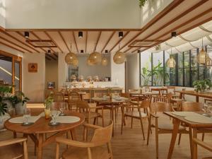 尖竹汶The Motifs Eco Hotel - SHA Extra Plus的餐厅设有木桌、椅子和窗户。