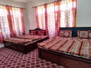 斯利那加Hotel city way的配有窗帘和窗户的客房内的两张床