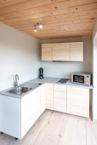 西内Autant pour toi的厨房配有白色橱柜和木制天花板