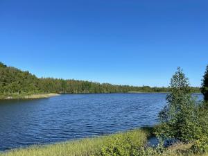 TingsrydCottage with beautiful nature, open landscape, forest and lakes I X I Stuga med fin natur, öppna landskap, skog och sjöar的一大片水,有树在背后