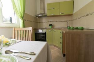 察夫塔特Apartments Miljanic的厨房配有绿色橱柜和一张带白色桌布的桌子。