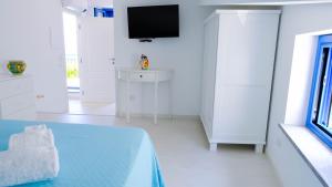 卡普多兰多Villa dei Due Ulivi的白色卧室设有一张床和墙上的电视
