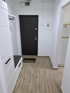 札勒乌Apartament 2 camere的走廊上设有黑色的门,铺有木地板