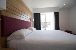 卡坦扎罗丽都PM Hotel的卧室配有一张大白色床和窗户