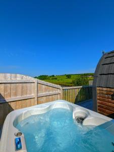 KeltyPond View Pod 2 with Private Hot Tub -Pet Friendly- Fife - Loch Leven - Lomond Hills的后院的热水浴池,设有木栅栏