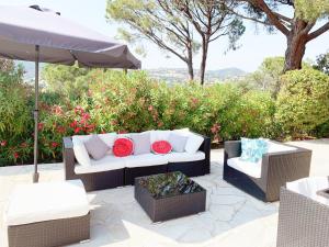 圣马克西姆Villa avec piscine privée的天井上配有沙发和两把椅子及遮阳伞