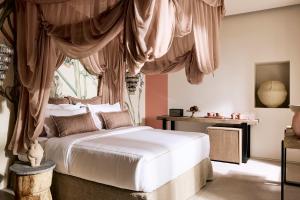 普拉卡米洛斯Niove Suites Milos的卧室配有带窗帘的白色床