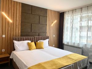 旧扎戈拉特拉亚娜酒店的一间卧室配有带白色床单和黄色枕头的床。