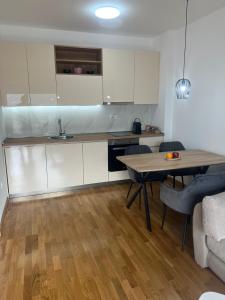 布德瓦Seaview Apartment Jana的厨房配有白色橱柜和木桌