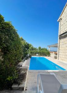 波尔Villa Ardura - island holiday residence **** Bol. Island Brač的一座蓝色的游泳池,位于一座建筑旁的院子内