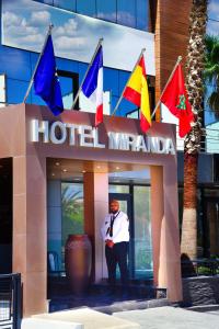 丹吉尔MIRANDA HOTEL - Tanger的站在酒店前方,有旗帜的人