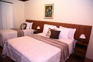 坎波斯杜若尔当Pousada Miraflores的一间卧室配有两张带枕头的床