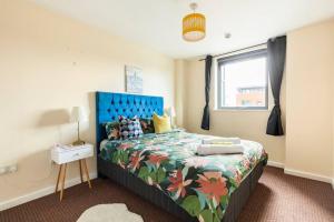 曼彻斯特Mosh Aparthotel Salford的一间卧室配有一张带蓝色床头板的床和窗户