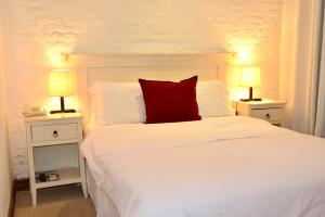 科洛尼亚-德尔萨克拉门托唐安东尼奥波萨达宾馆的卧室配有白色的床和红色枕头