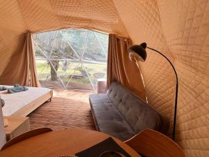 沃尼扎Manna Gea Glamping Domes的一间设有沙发的帐篷客房,配有窗户