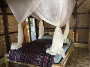 Hitokalak日落小屋旅馆的一间卧室配有带窗帘的天蓬床