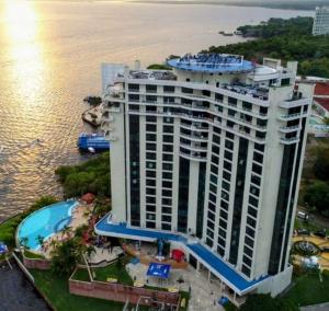 马瑙斯Flat Hotel Tropical Executive Praia Ponta Negra的一座大型建筑,在水边设有游泳池