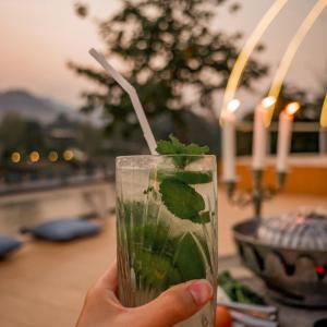 塞友Baanpufa Resort的手持一杯绿色饮料的手