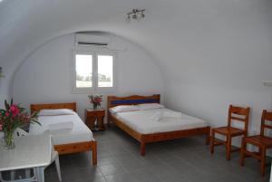 佩里萨阿波罗客房旅馆的一间设有两张床和一张桌子及椅子的房间