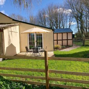 赫里福德Beautiful 1-Bed Lodge in Clifford Hereford的房屋,配有桌子、雨伞和围栏