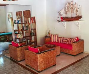 贝岛Villa Les Cocotiers的客厅配有柳条家具,墙上有一条船