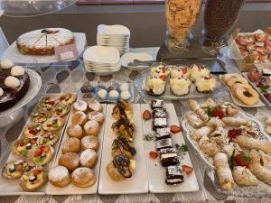 里米尼帕乌拉别墅酒店的一张桌子,上面摆放着各种糕点和蛋糕
