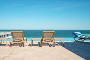 北马马亚-讷沃达里Castelana Infinity Beach Pool&Spa Mamaia Nord的一组椅子和一张桌子,靠近大海