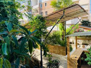 伏罗拉Adriatic Hostel Vlora的一个带木制凉亭和木桌的花园