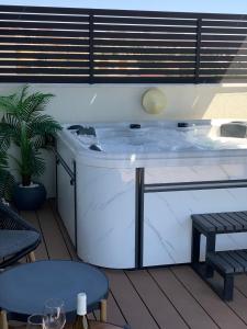埃拉特Sea view penthouse Private rooftop jacuzzi的甲板上的热水浴池配有桌子和长凳