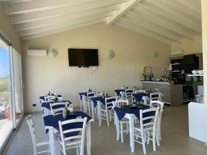 特乌拉达Is Arenas Biancas Agriturismo的用餐室配有蓝色桌子和白色椅子