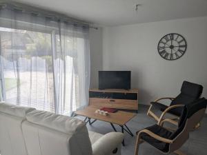 DigosvilleGîte entre Cherbourg et Val De Saire的客厅配有沙发、电视和椅子