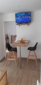 安德诺莱斯贝恩La Petite Perle的一张桌子、两把椅子和墙上的一台电视