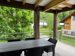 安特特泽Wunderschöne Wohnung am See mit Sauna & Whirlpool的木制门廊,甲板上配有桌椅