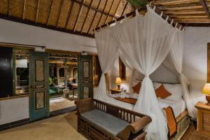 乌布Roshan Ubud Villa的一间卧室配有一张天蓬床和椅子