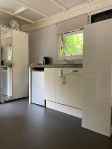 斯哈伦代克Meer en Zee的厨房配有白色橱柜和窗户。