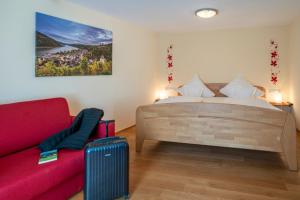 巴哈拉赫艾康尼歇霍夫酒店的一间卧室配有一张床和一张红色的沙发